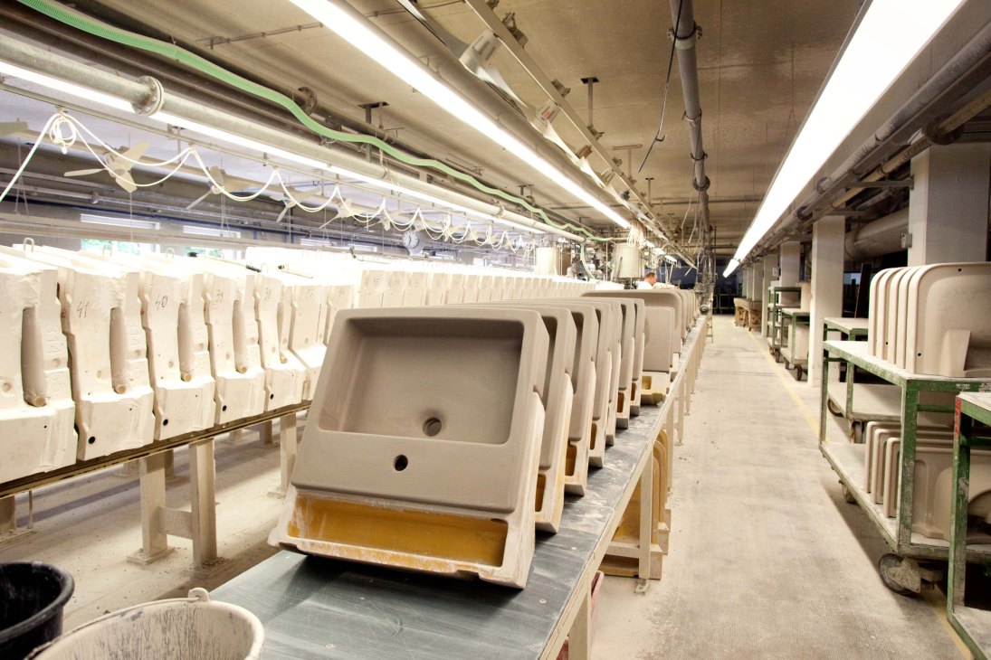 Rows of white ceramic sinks in various stages of production at Duravit manufacturing facility.