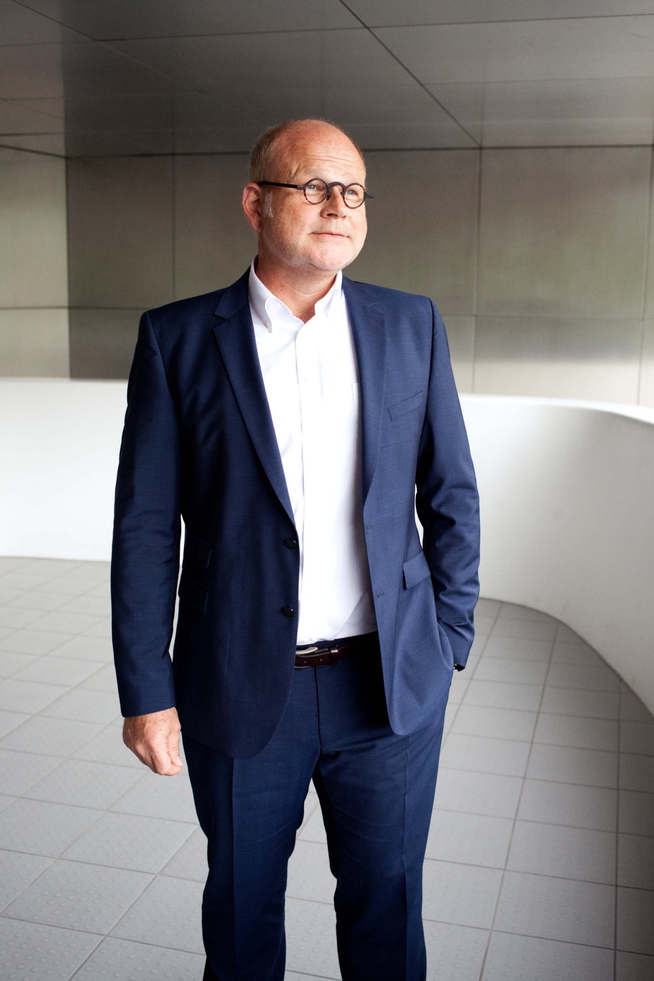 Mathias Schott, head of marketing at Duravit, standing in a modern office corridor wearing a navy blazer and glasses.