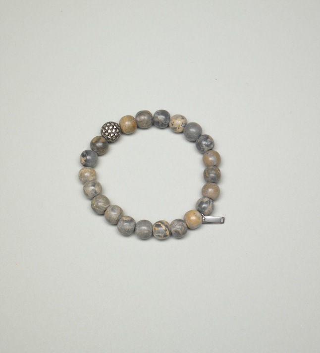 Beaded bracelet with gray and tan spheres and decorative metal accents on white background.