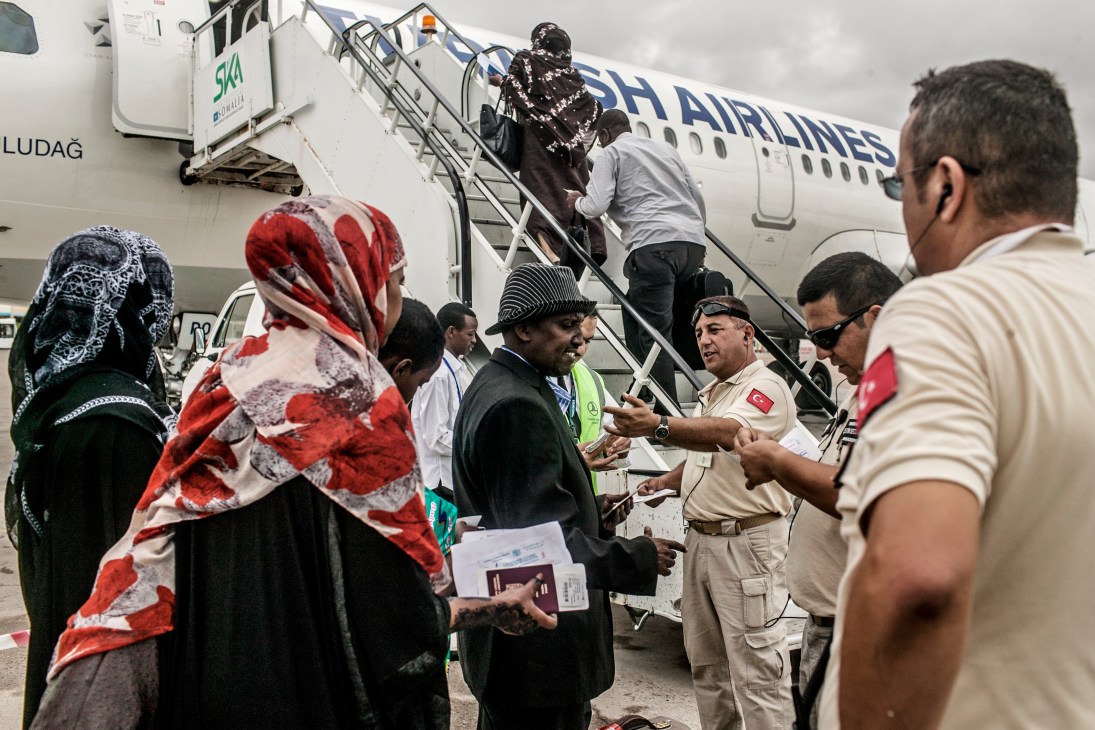 Passengers boarding a Turkish Airlines aircraft via stairs, with airport staff in uniform managing the queue.