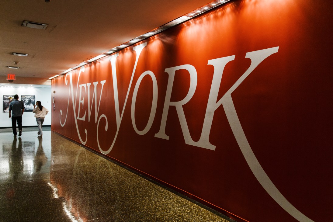 New York magazine office lobby with large red wall sign and two people walking