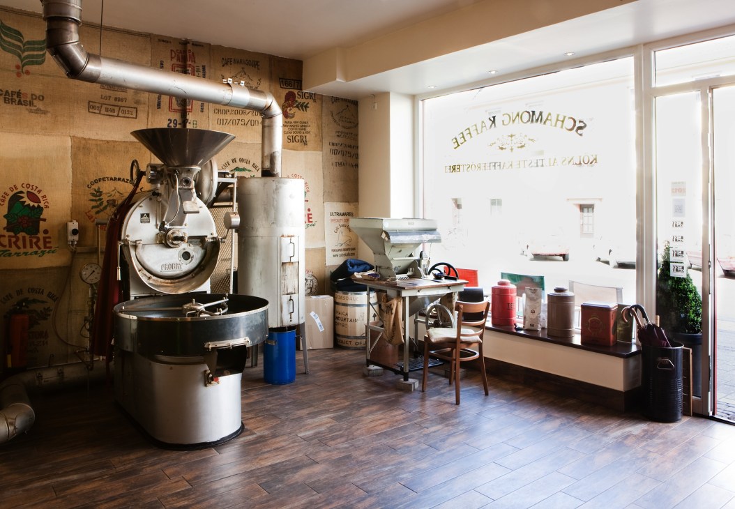 Interior of Schamong Kaffee coffee roastery with vintage roasting equipment and burlap sacks.