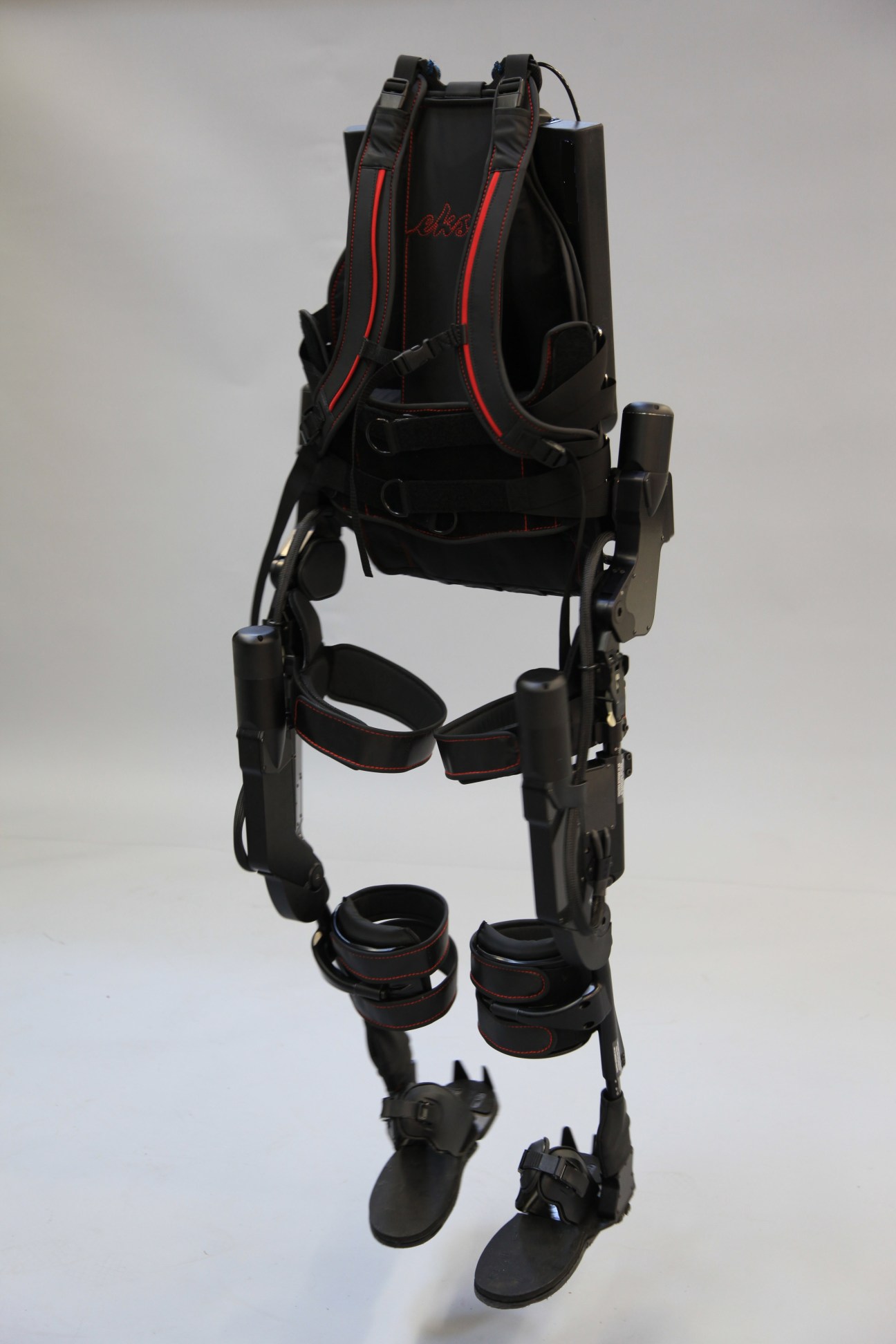 Ekso Bionics exoskeleton device with black frame, red accents, and ankle attachments displayed against white background.