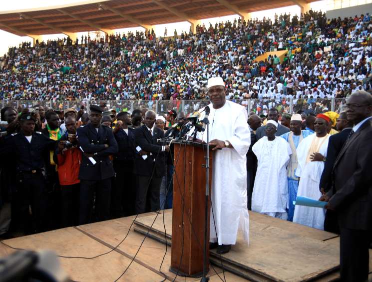 Mali presidential candidate Ibrahim Boubacar Keïta speaking at a podium during a campaign rally in a crowded stadium.