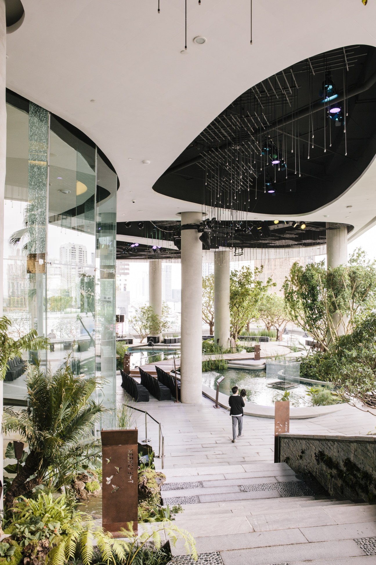 EmQuartier's open-air garden with lush plants, modern architecture, and Bangkok skyline views