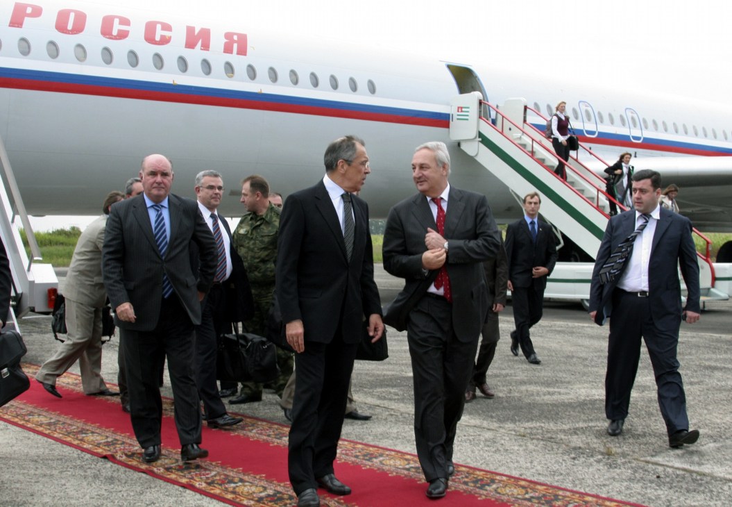 Sergei Bagapsh and Sergei Lavrov walk on a red carpet in front of a Russian aircraft at Sukhumi Airport.