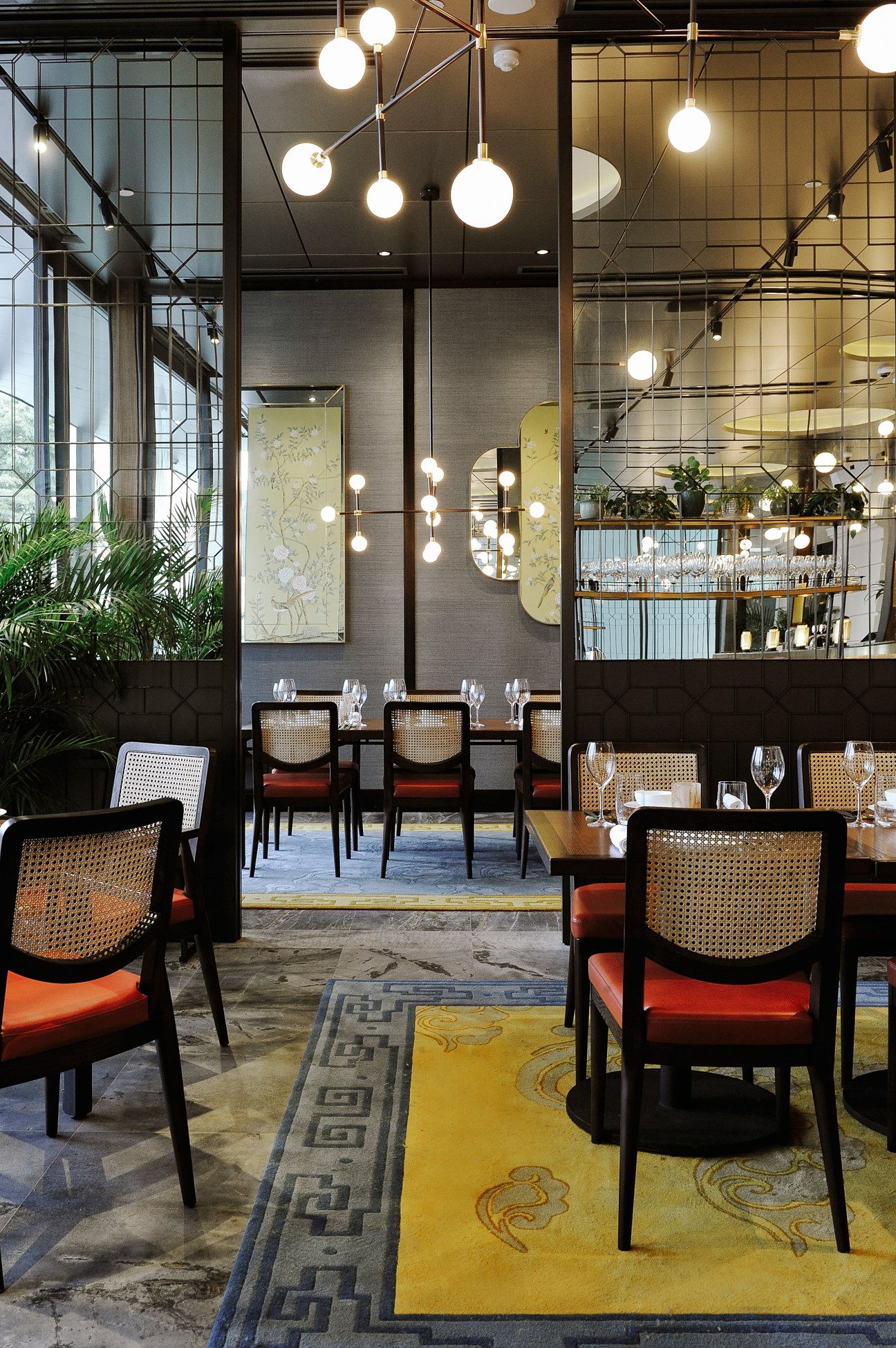 Modern restaurant interior with cane-back chairs, spherical pendant lights, and industrial design elements