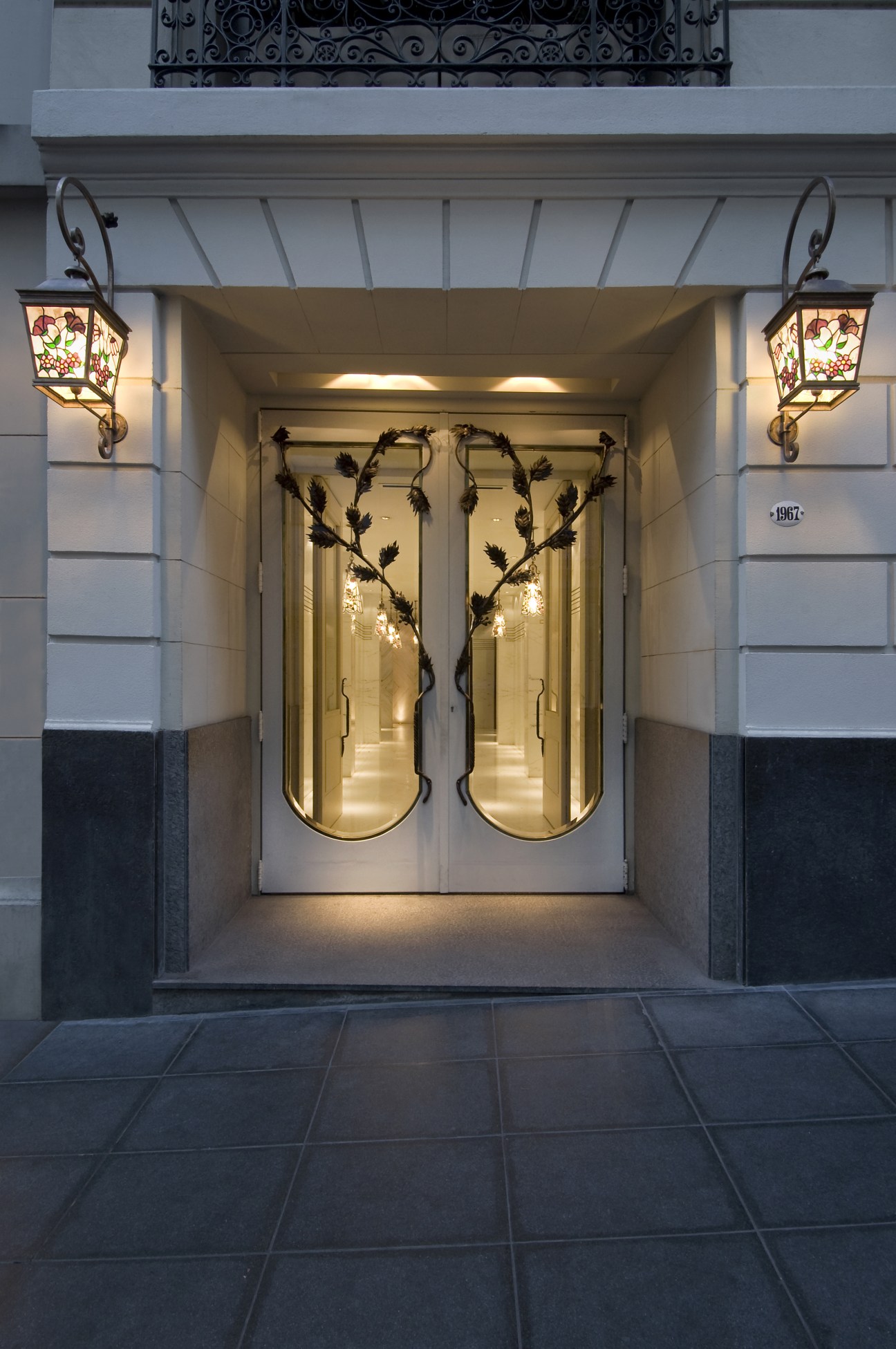 Elegant entrance to Hub Porteño with ornate brass-framed doors and decorative wall sconces.