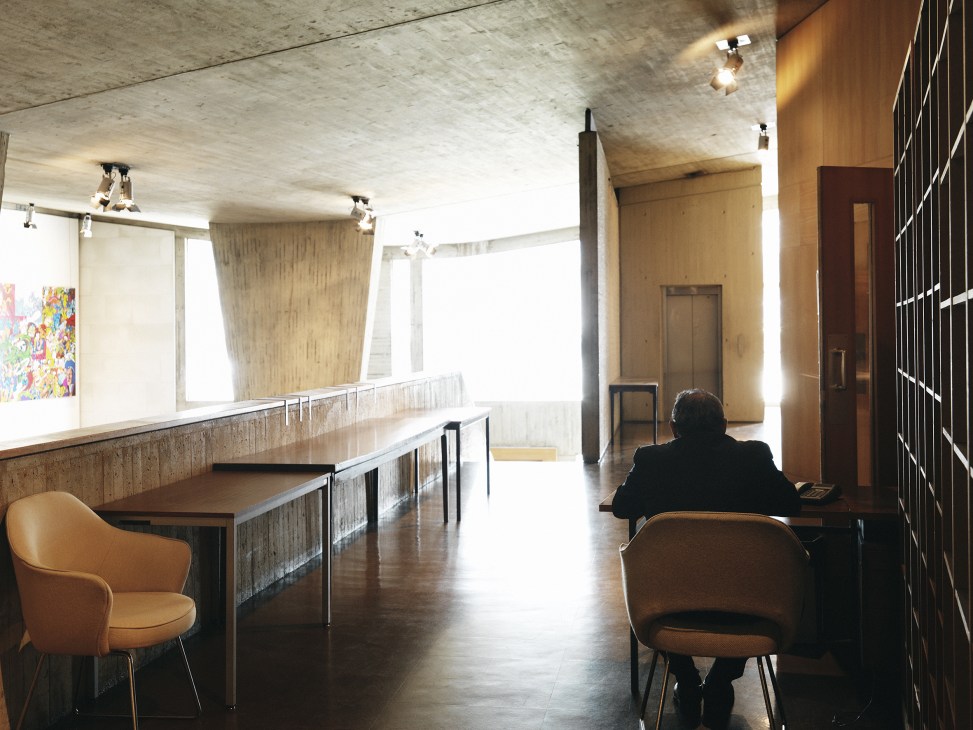 Interior of a modernist conference room at Unesco with concrete ceiling, wooden furniture, and a person seated at a table.