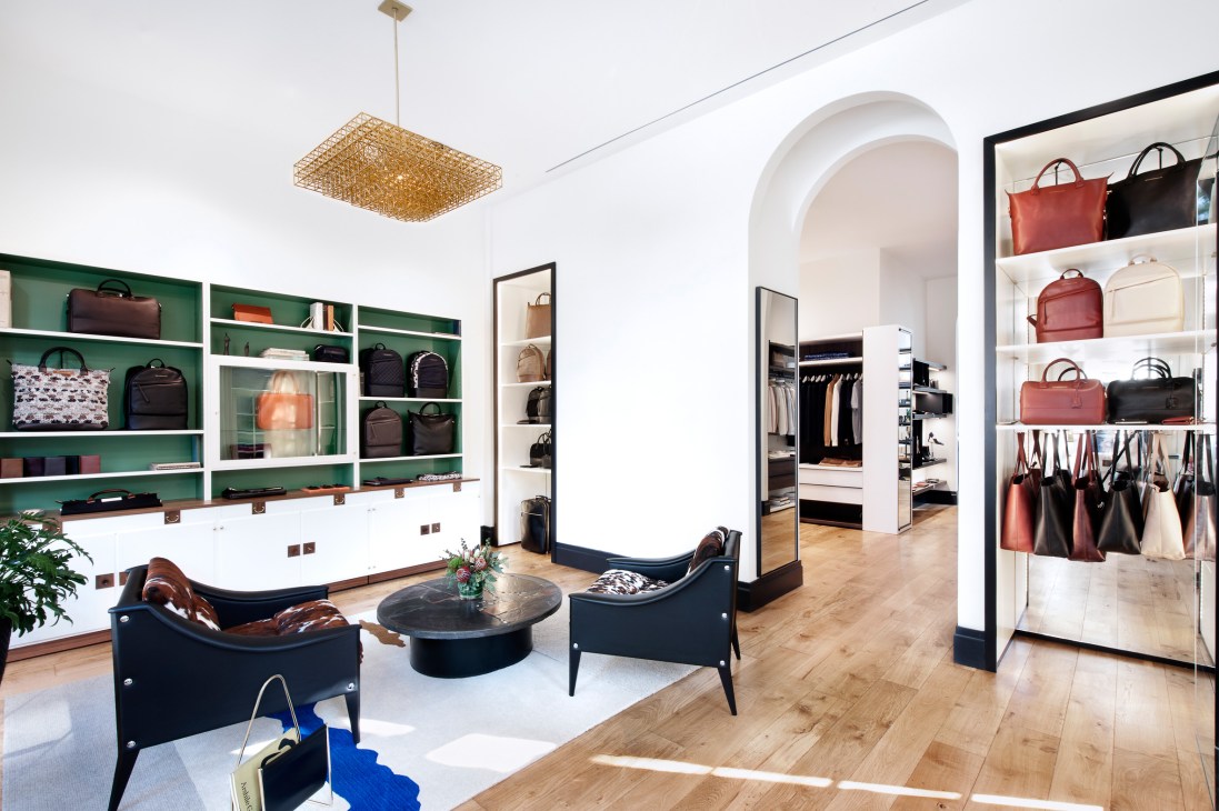 Want Les Essentials boutique interior with green shelving, leather bags, and lounge seating in New York.