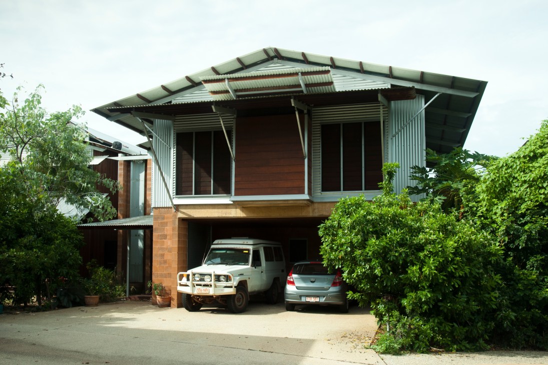 Modern tropical house with angled metal roof, large windows, brick base and carport in Darwin suburb.