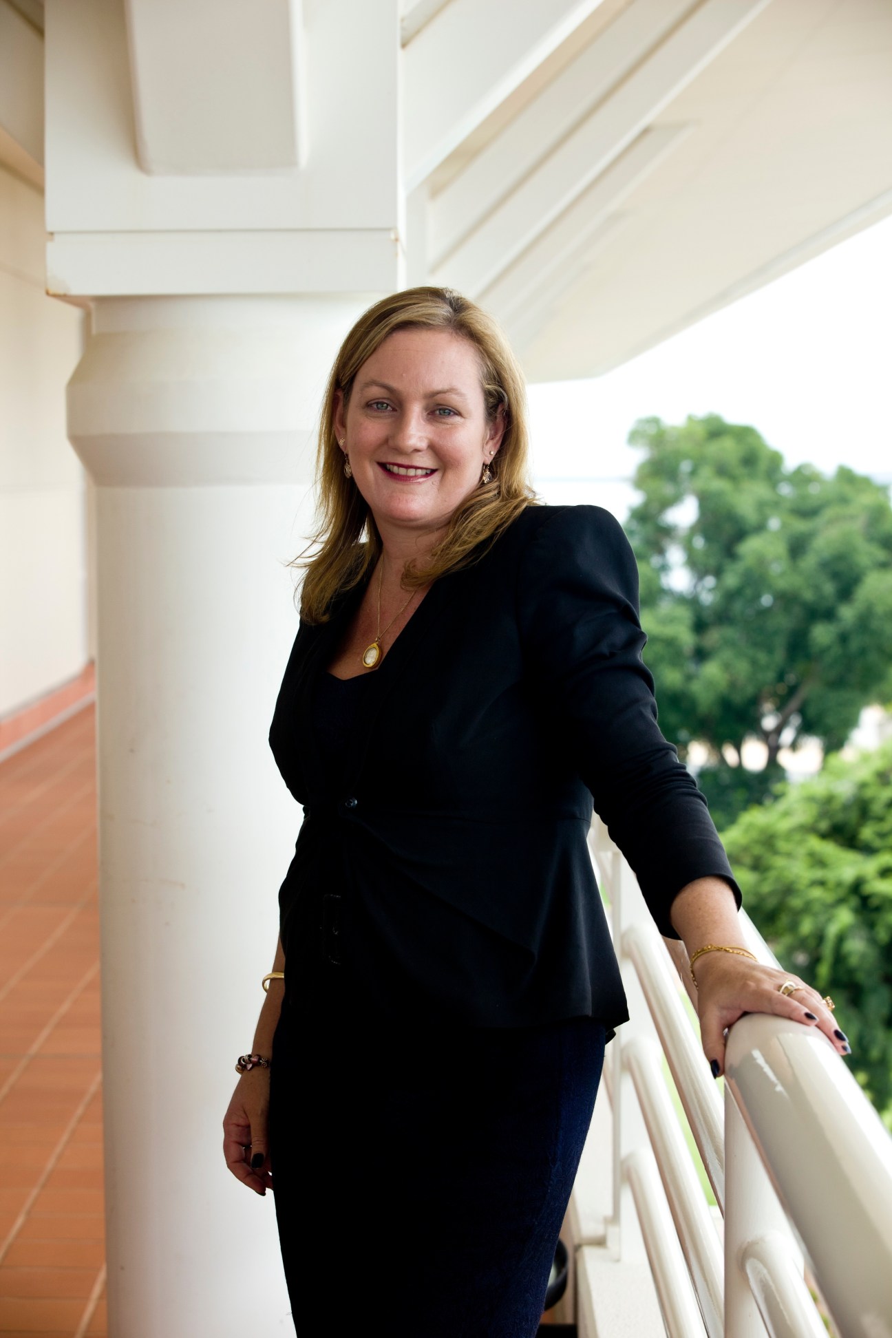 Deputy chief minister of the Northern Territory, Delia Lawrie, poses in a black blazer on a covered porch with white columns.