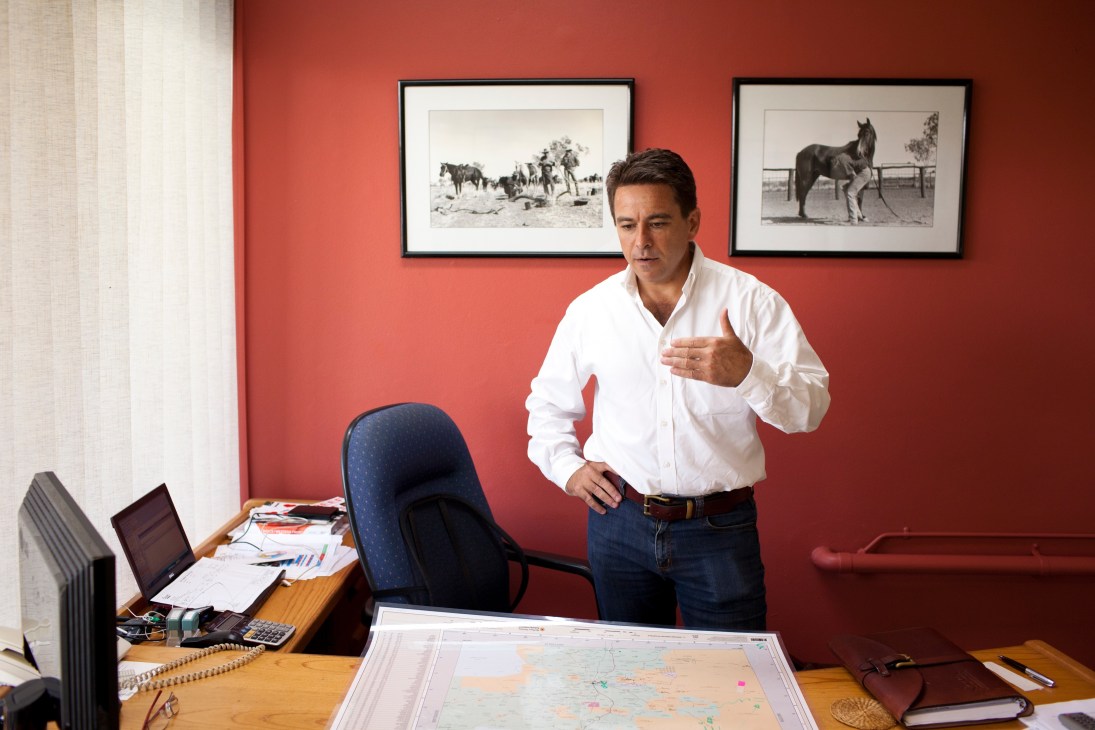 Luke Bowen, executive director of NT Cattlemen's Association, stands in an office with red walls and horse photographs.