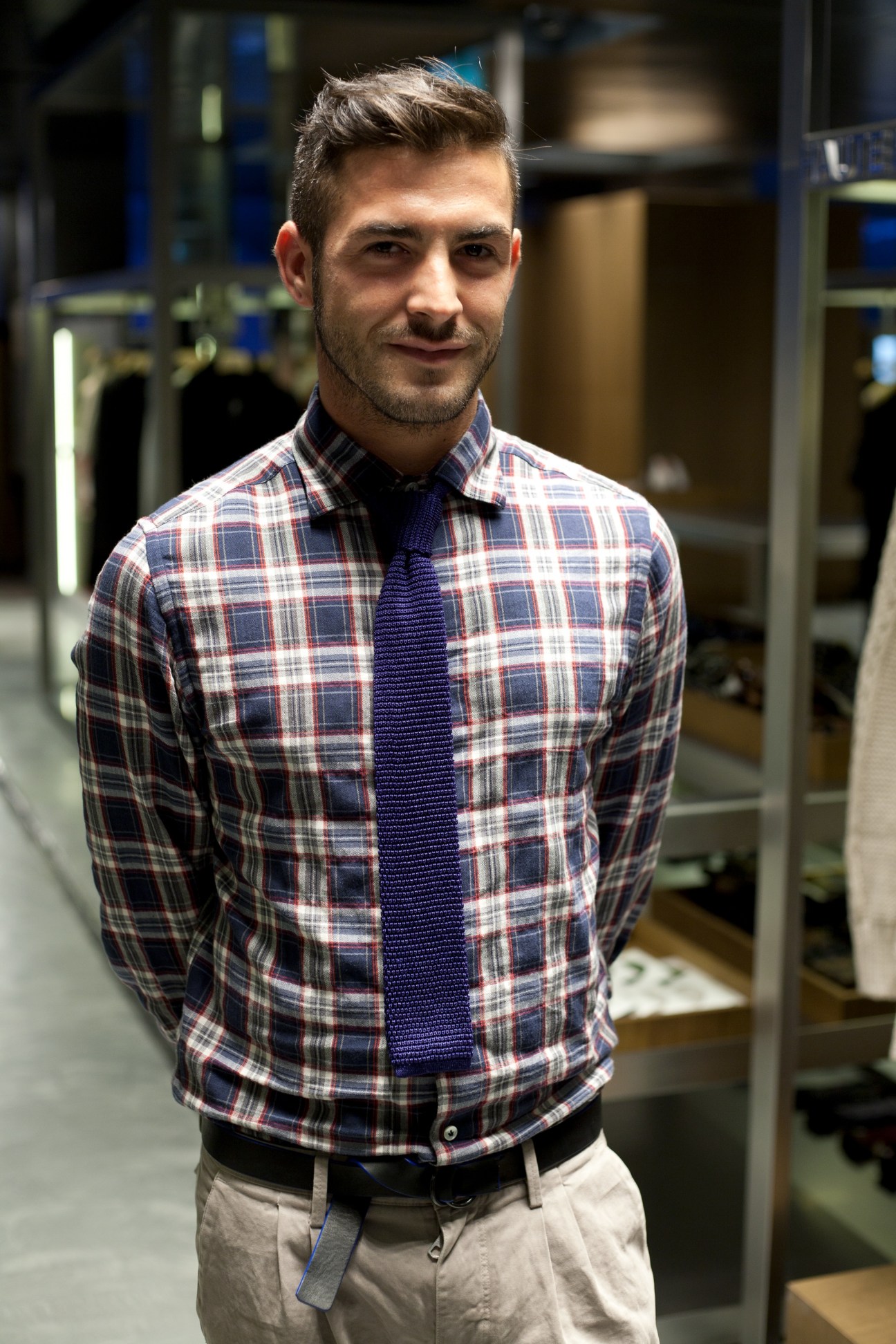 Man in plaid shirt and navy tie standing in modern retail interior