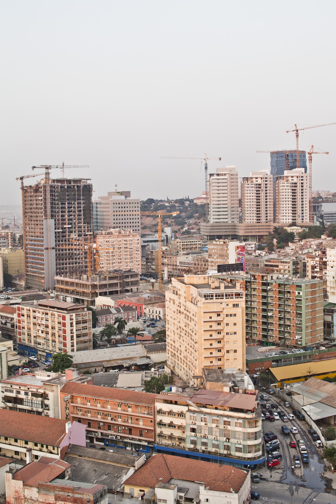 Luanda's skyline featuring modern high-rise buildings and construction cranes alongside lower-rise residential buildings.