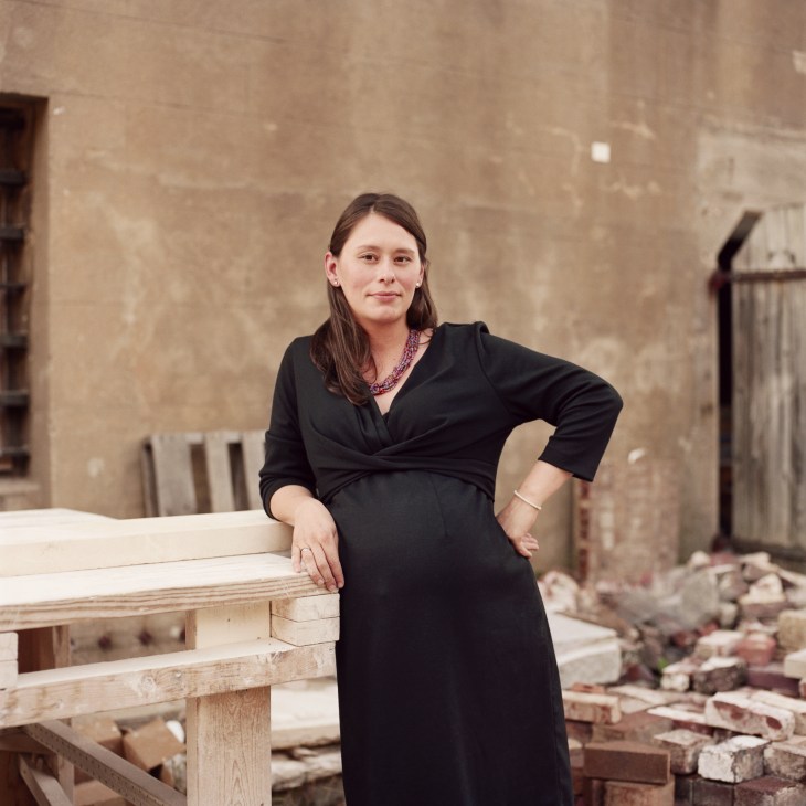 Beverley Payne, student coordinator, posing against a weathered brick wall at the American College of Building Arts.