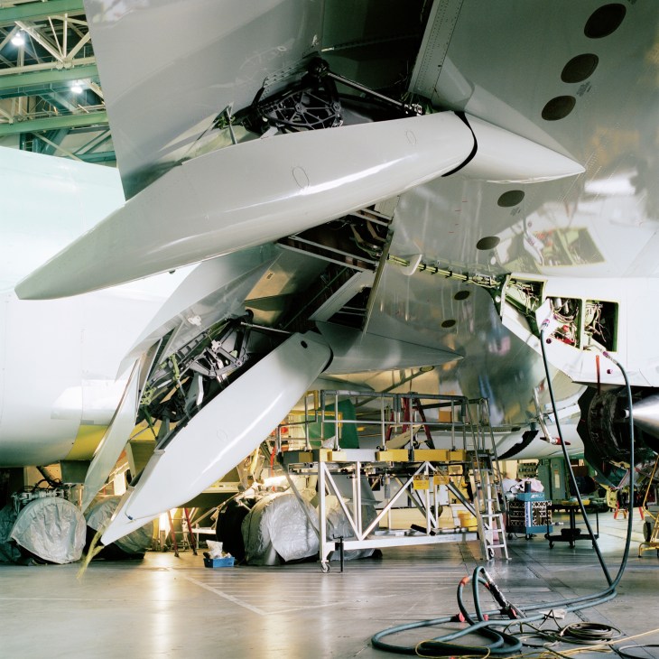 Close-up of Boeing 747-8 aircraft nose section and wing assembly during construction in factory hangar.