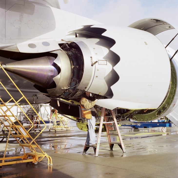 Technician working on a large GEnx-2B engine mounted on a Boeing 747-8 aircraft on the flight line.
