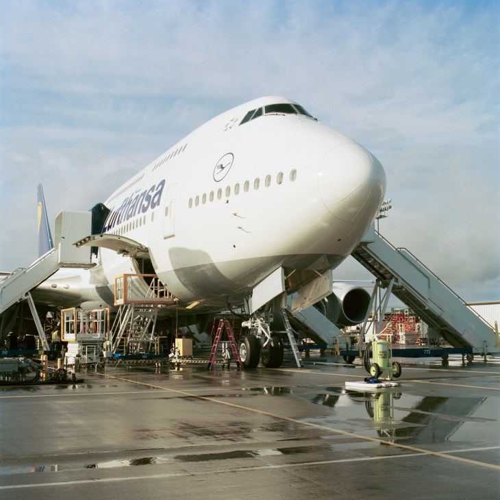 Lufthansa Boeing 747-8 aircraft undergoing final assembly with ground equipment and stairs surrounding the fuselage.