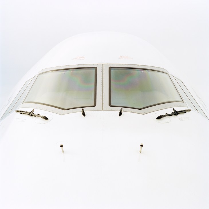Two large rectangular cockpit windows of a Boeing 747-8 aircraft against white fuselage.