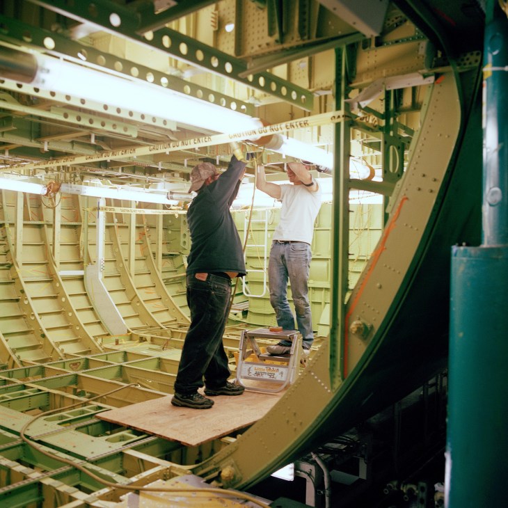 Two workers install components inside the fuselage of a Boeing 747-8 aircraft during assembly.
