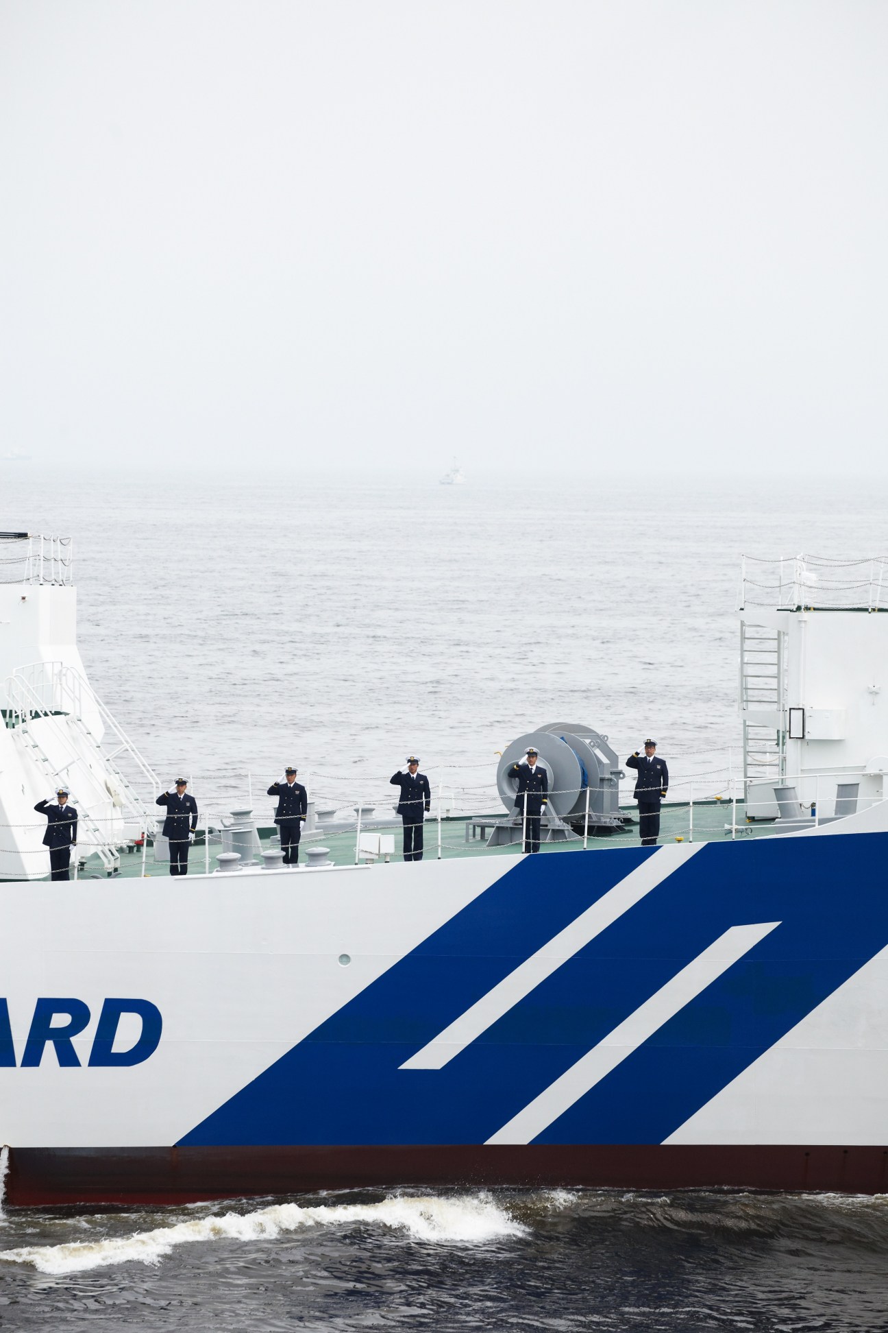 Japan Maritime Self-Defence Force escort ship with uniformed personnel lined up on deck during a Japan Coast Guard fleet viewing event.
