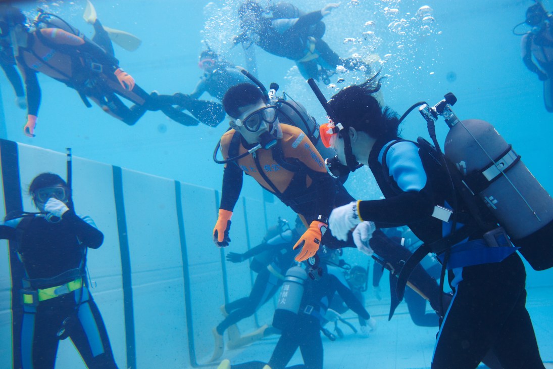 Japan Coast Guard academy students diving underwater during training in the pool.
