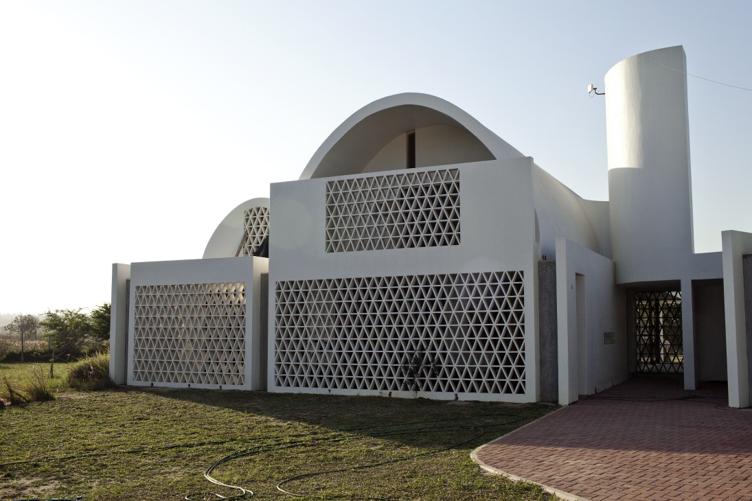 White modernist house with geometric triangular lattice screens and curved concrete forms designed by Pancho Guedes.