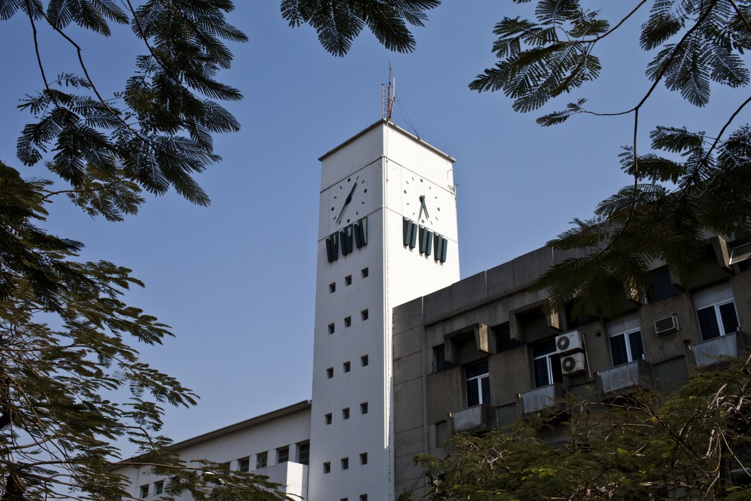 Radio Mozambique clock tower with white concrete tower and modernist design against blue sky
