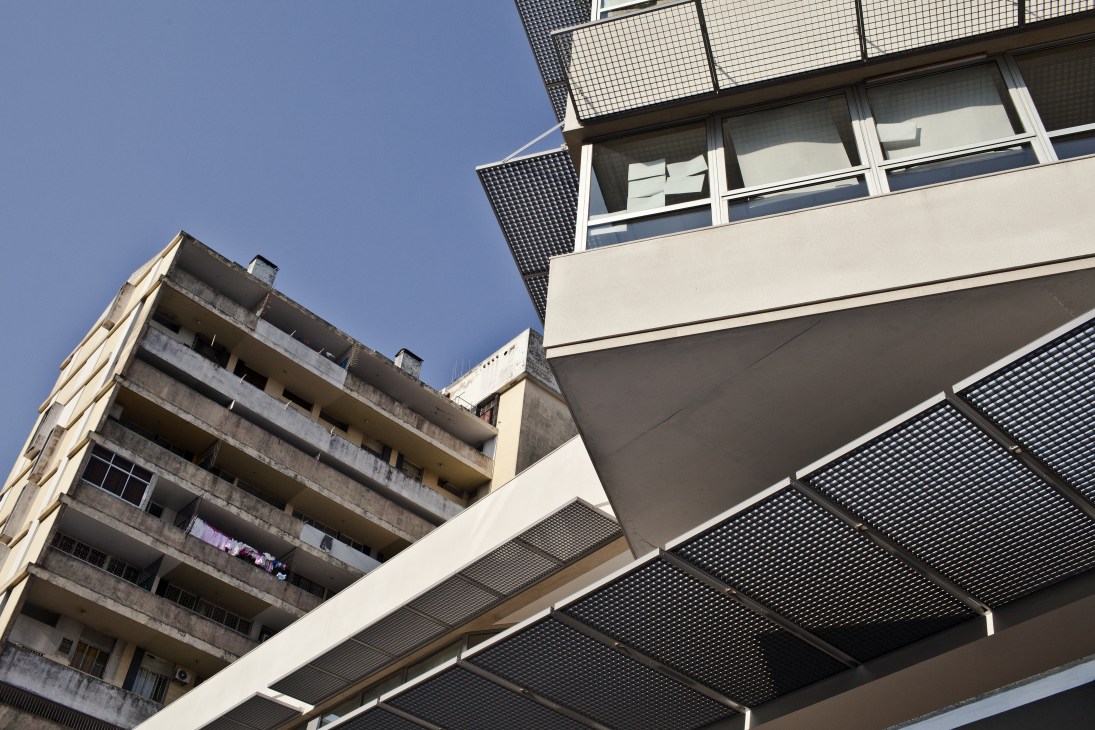 Modern white concrete building with horizontal elements and mesh screens designed by José Forjaz.
