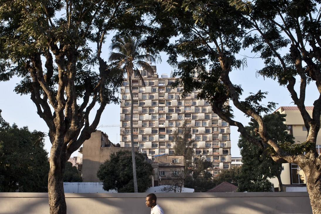 A 1970s apartment building in Maputo framed by acacia trees lining a street.