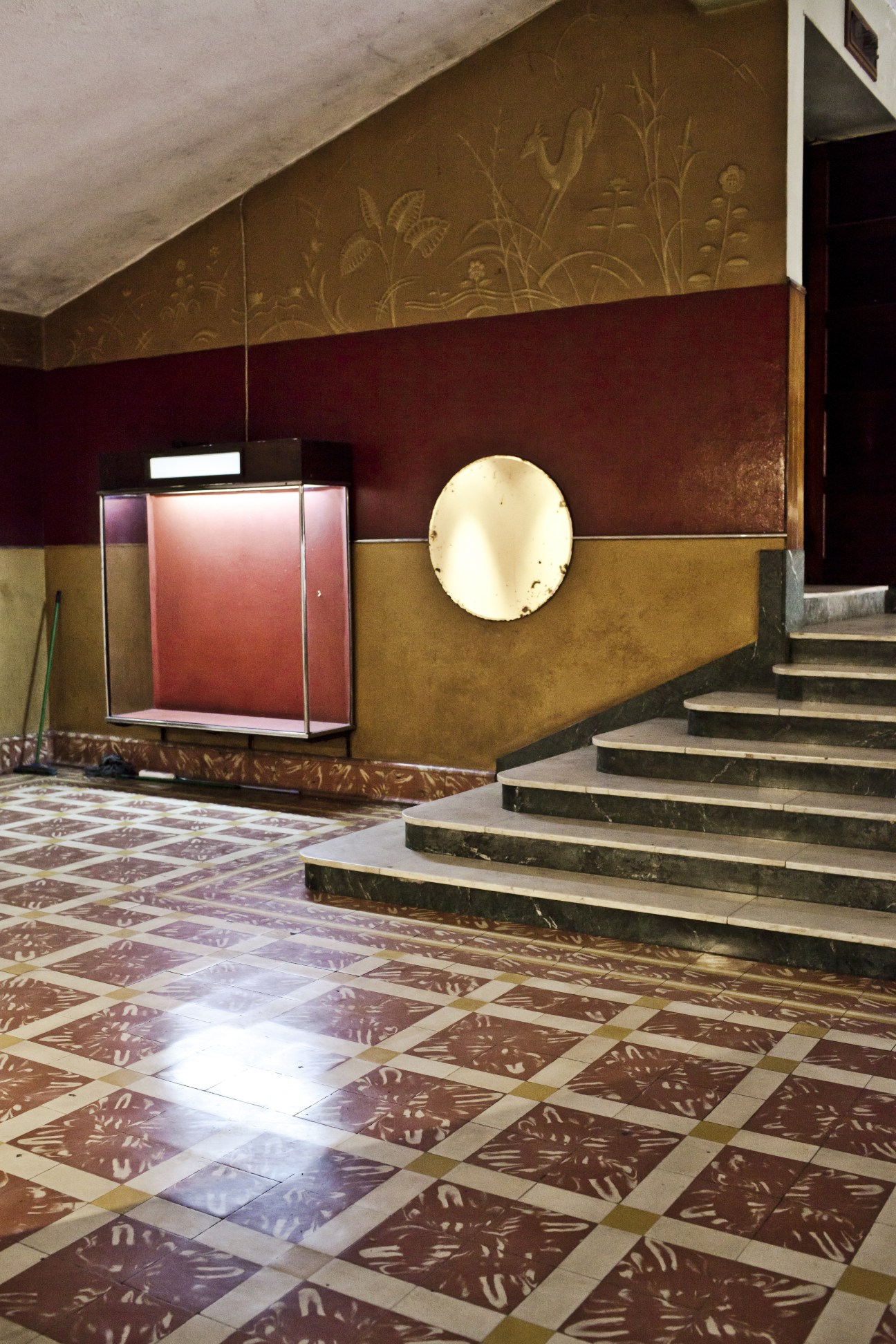 Interior of Cine Africa foyer with burgundy walls, decorative tilework, and modernist design elements.