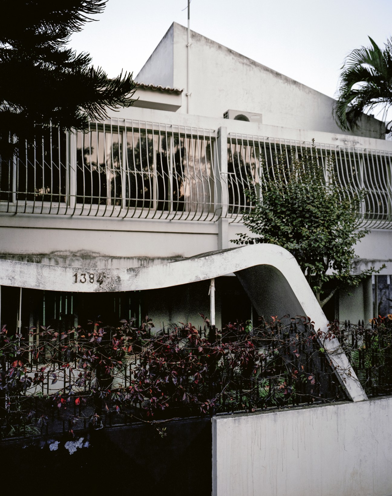 White modernist concrete building with curved architectural elements and metal railings, designed by Pancho Guedes in the 1950s.