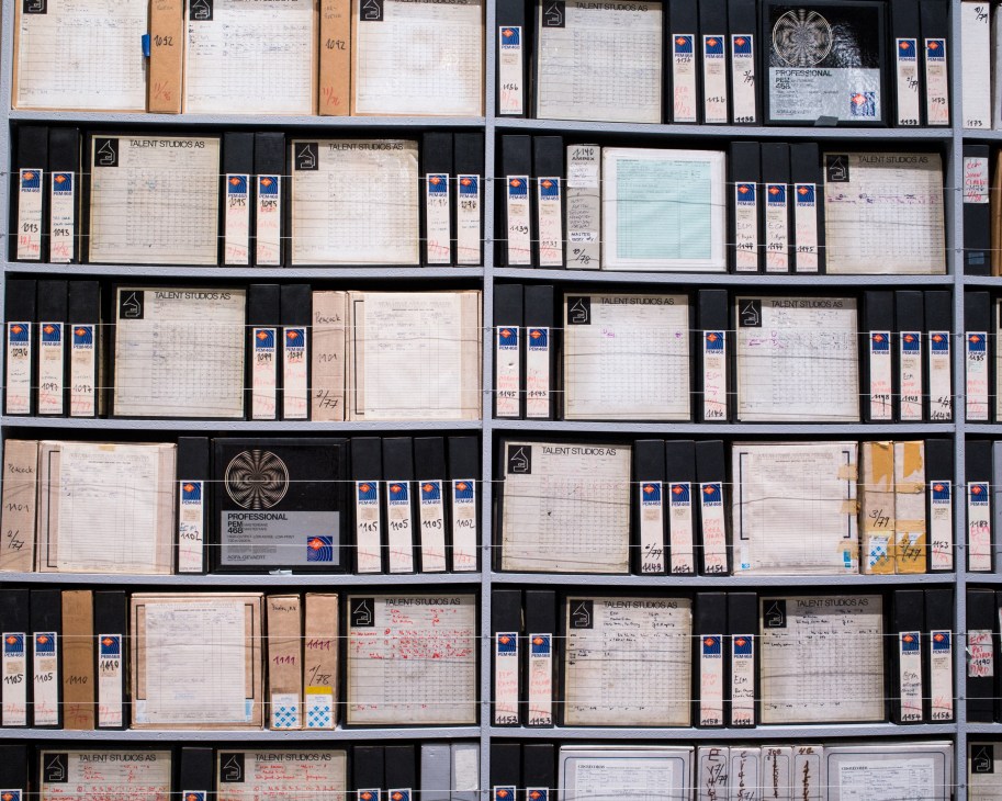 Shelving unit displaying organized archival documents and materials from ECM record label with numbered spines and labels.