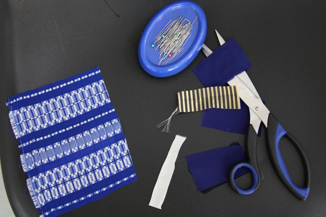 Zeus + Dione patterned fabrics in blue and white displayed with sewing supplies on dark background.