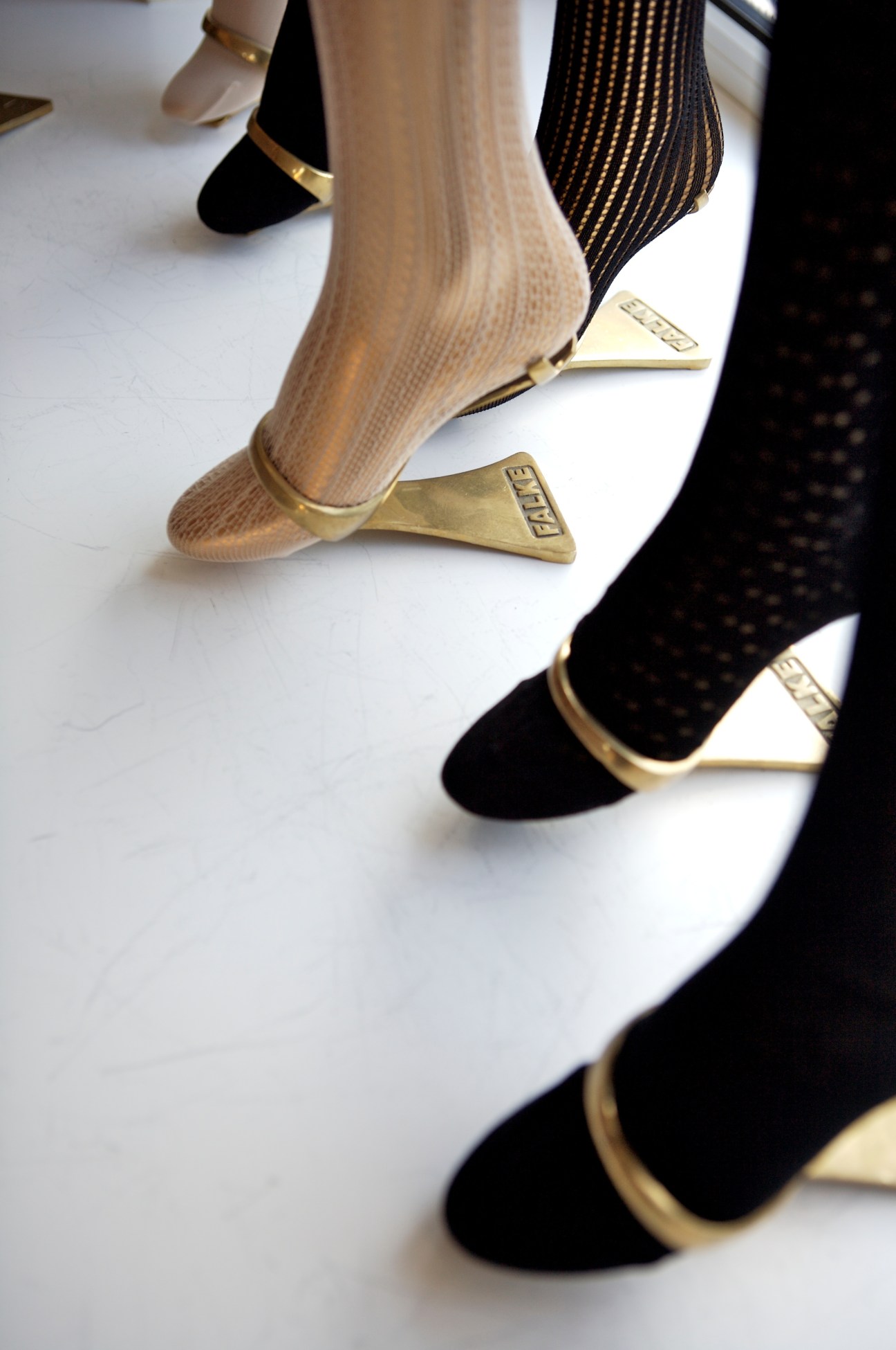 Falke tights displayed in the showroom featuring black and cream-colored pairs with gold trim details.