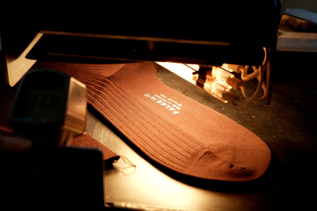 Falke logo printed on a brown sock under bright factory lighting.