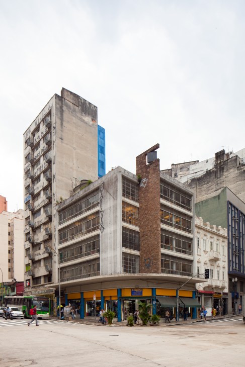 O Farol building exterior in São Paulo's Centro district with worn paint, blue and yellow storefront, and surrounding architecture.