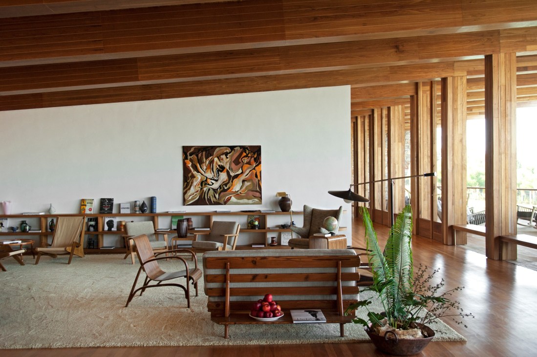 Mid-century modern interior with wooden furniture, artwork, and views to outdoor terrace at Fasano Boa Vista.