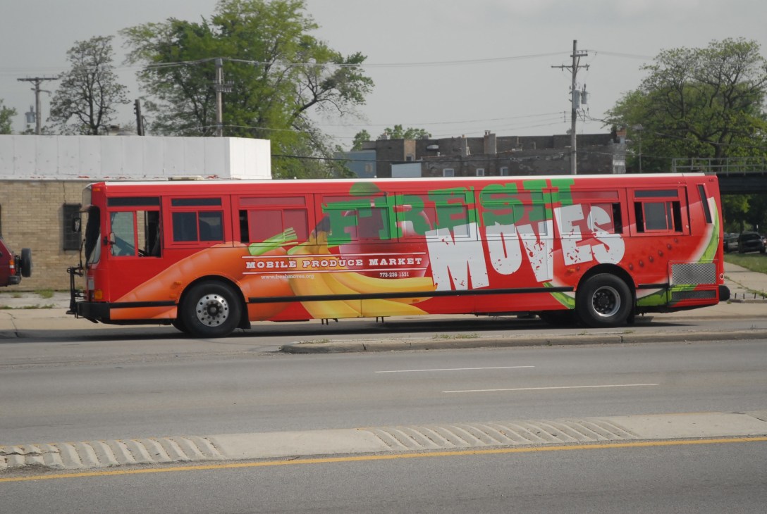 Red bus with Fresh Moves branding parked on a Chicago street serving as a mobile produce market.