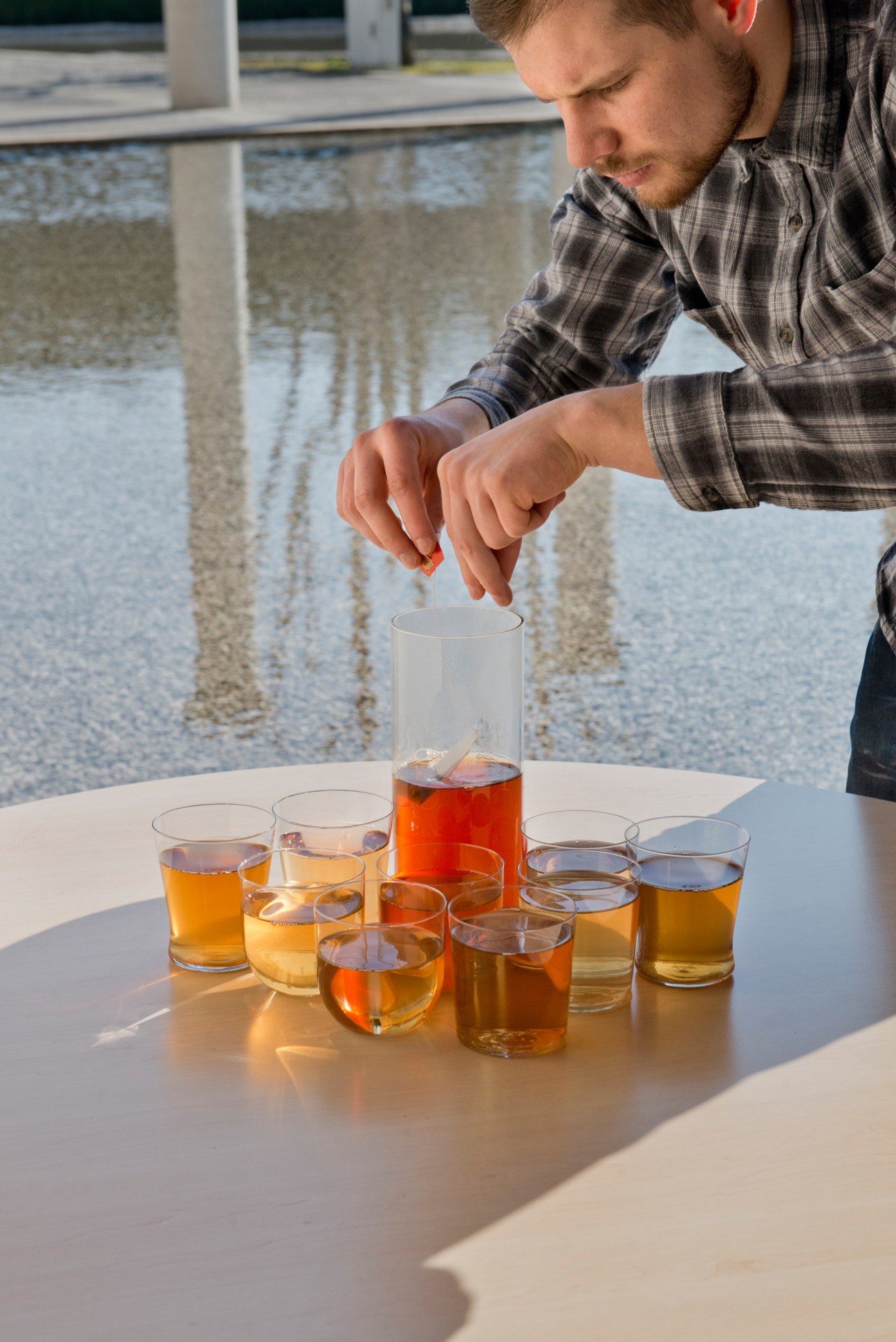 British designer Daniel Rous pouring tea into glasses of varying strengths for his hospitality project.