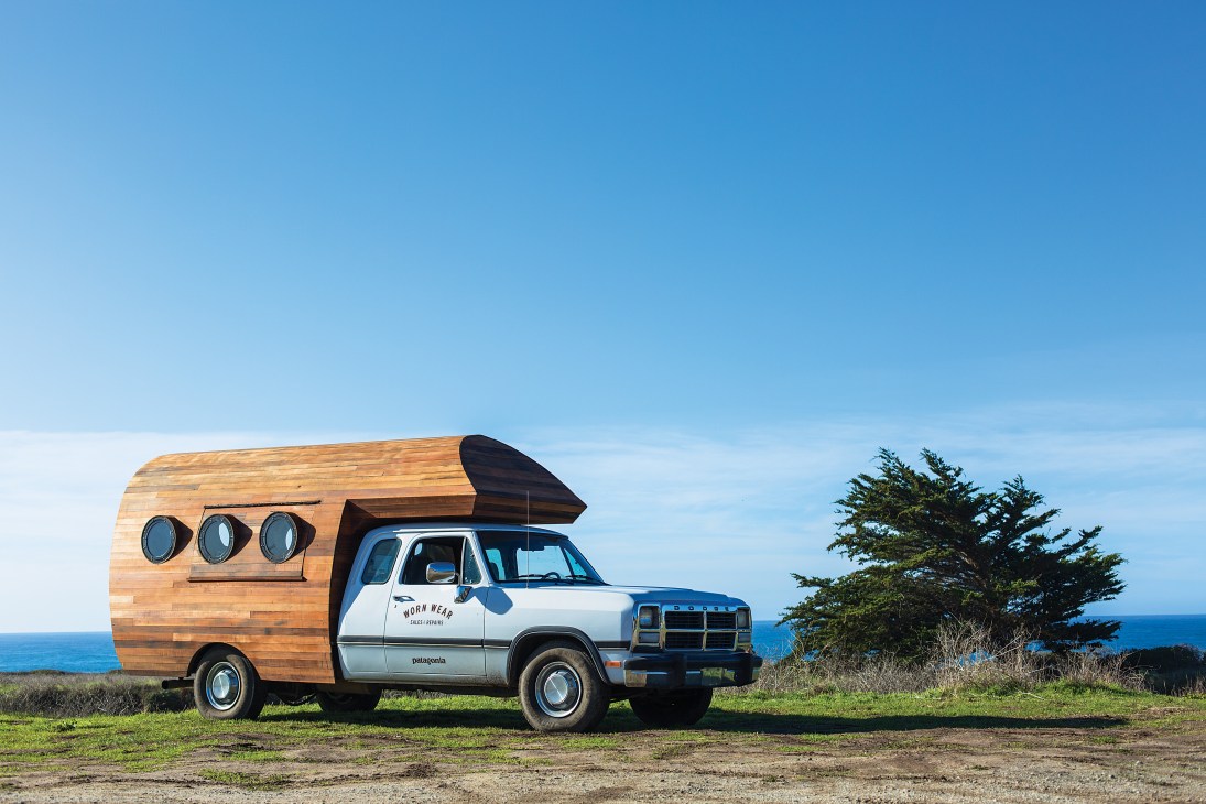 Patagonia's Worn Wear solar-powered camper van with salvaged redwood exterior parked by ocean.