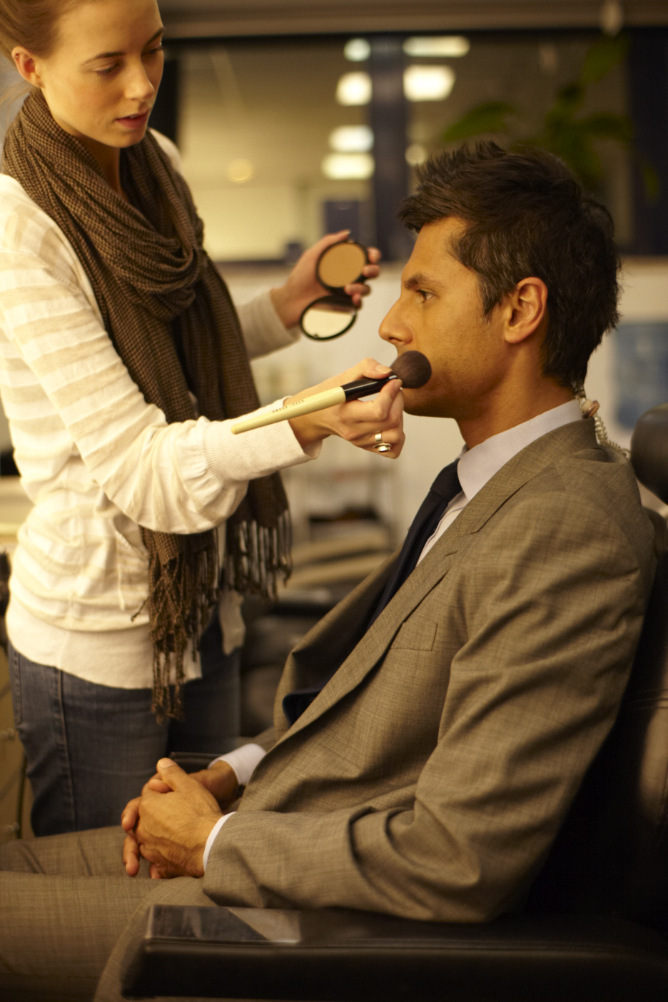 A makeup artist applies powder to sports reporter Rahul Pathak's face before going on air.