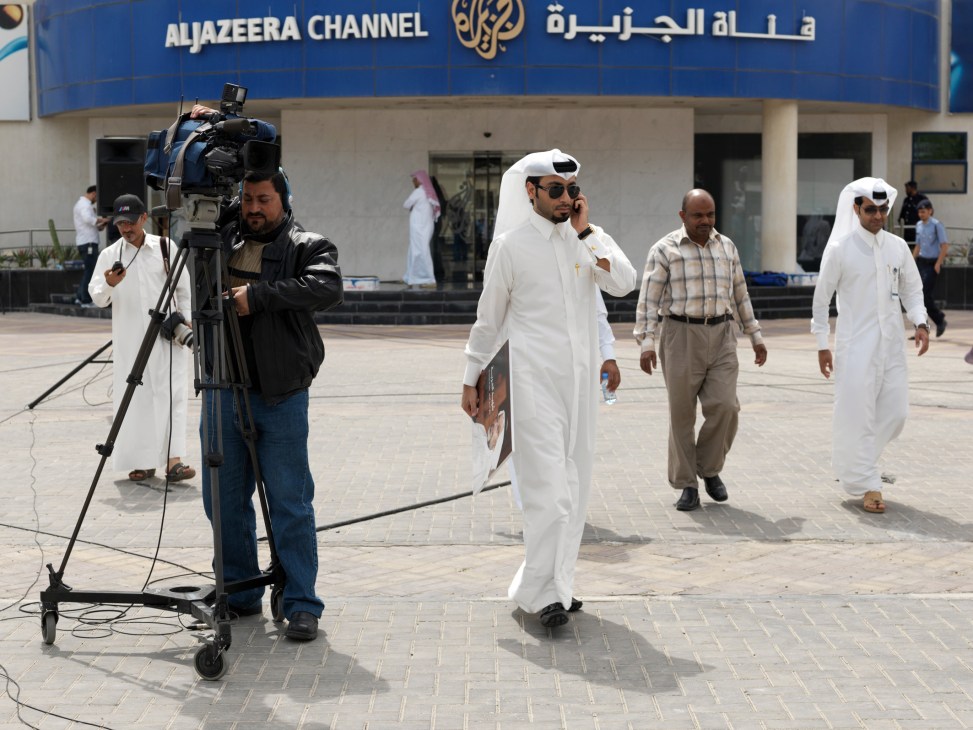 Film crew outside Al Jazeera Arabic studios building in Doha with signage visible.