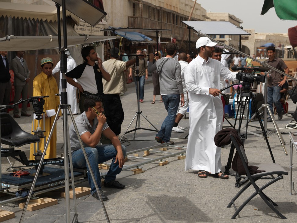 Film crew shooting a children's comedy production on a street with camera equipment and crew members.