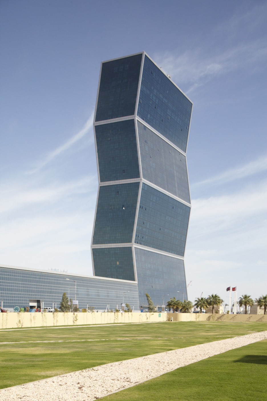 The Zigzag tower, a twisted skyscraper with geometric white-framed sections, stands against blue sky in Doha.