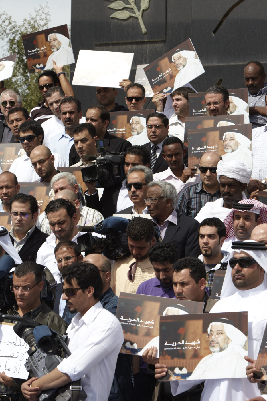 Al Jazeera staff holding memorial portraits of Ali Hassan Al Jaber at the cameraman's memorial in Doha.