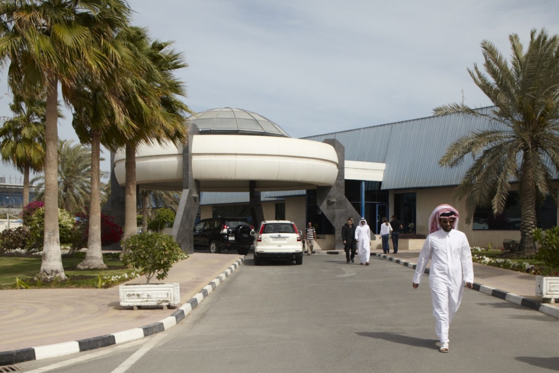 UFO-style entrance to Al Jazeera Arabic studios in Doha with futuristic dome architecture, palm trees, and people in traditional dress