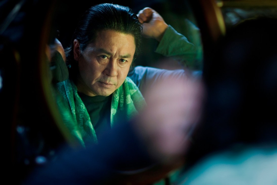 A man in a green jacket looks intensely at the camera in a scene from the film I Saw the Devil.