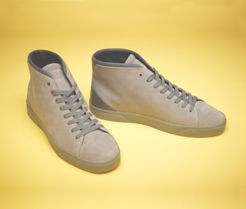 Pair of cream suede and goat's leather hi-top trainers with gray laces on a yellow background.